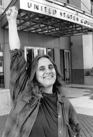 Judi Bari gives a confident raised fist salute outside the Oakland California Federal Courthouse. Photo by Xiang Xing Zhao for San Francisco Daily Journal, March 3, 1995